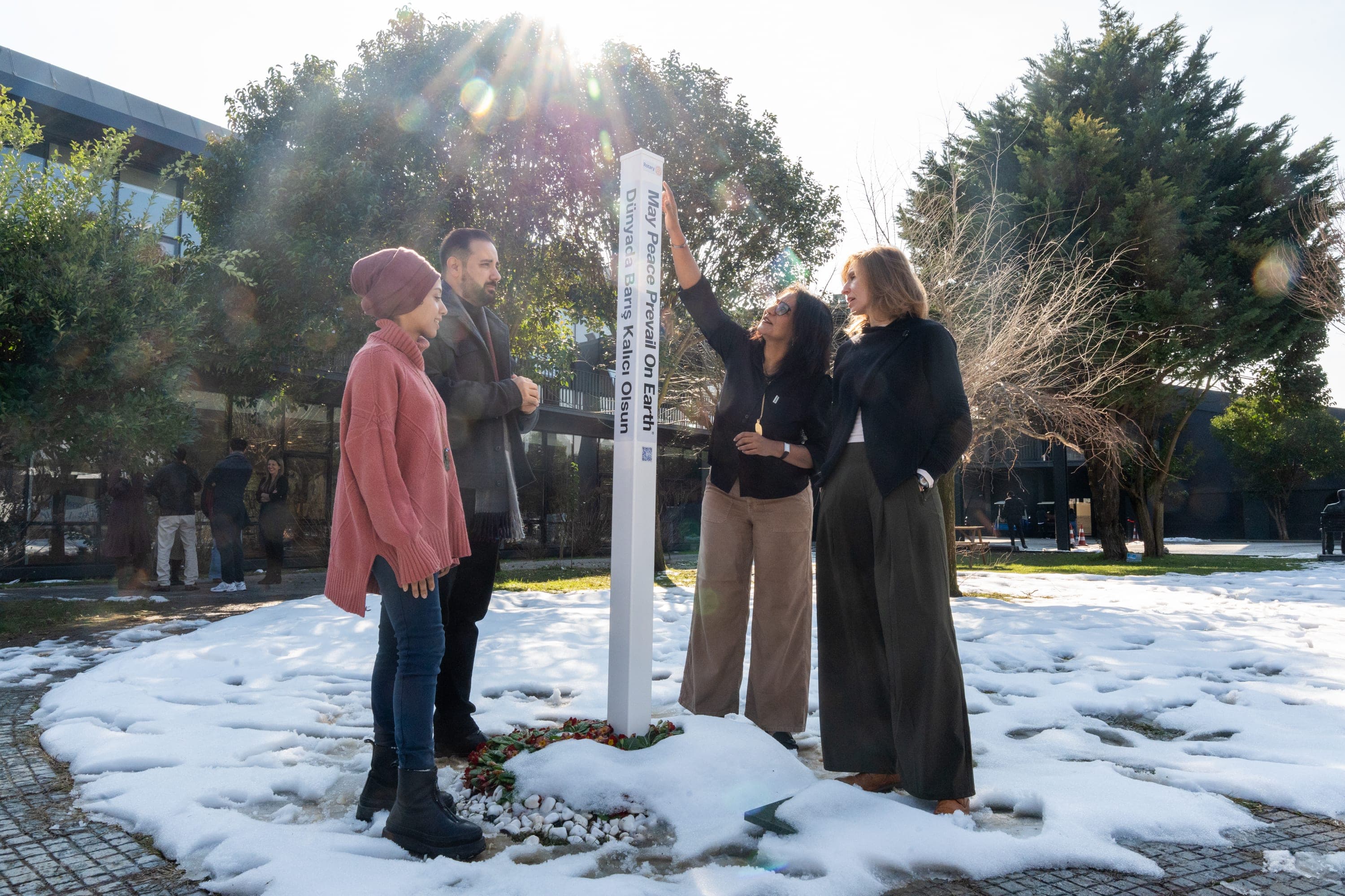 A group of people standing around a sign in the snow