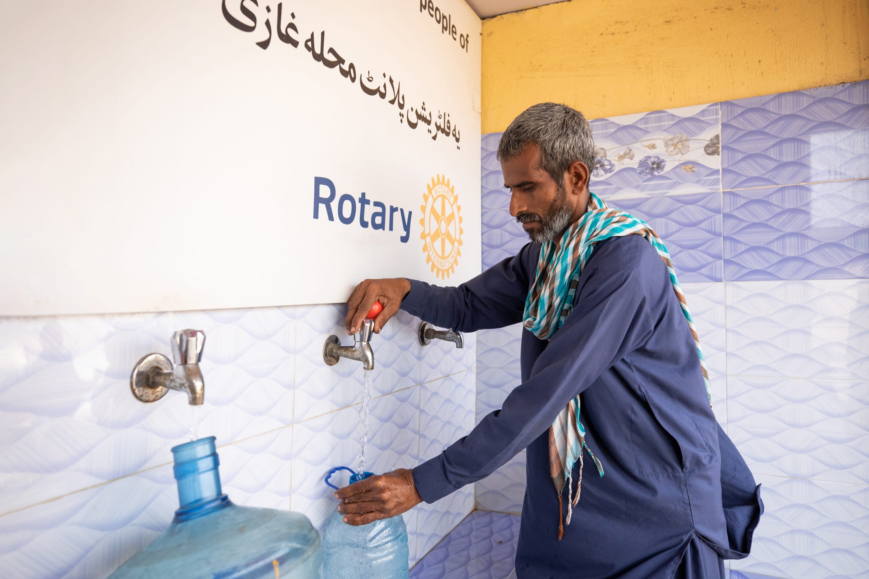 A man in a blue shirt is fixing a water faucet