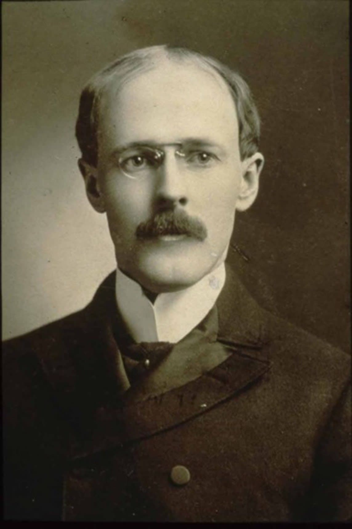 A black and white photo of a man with a mustache