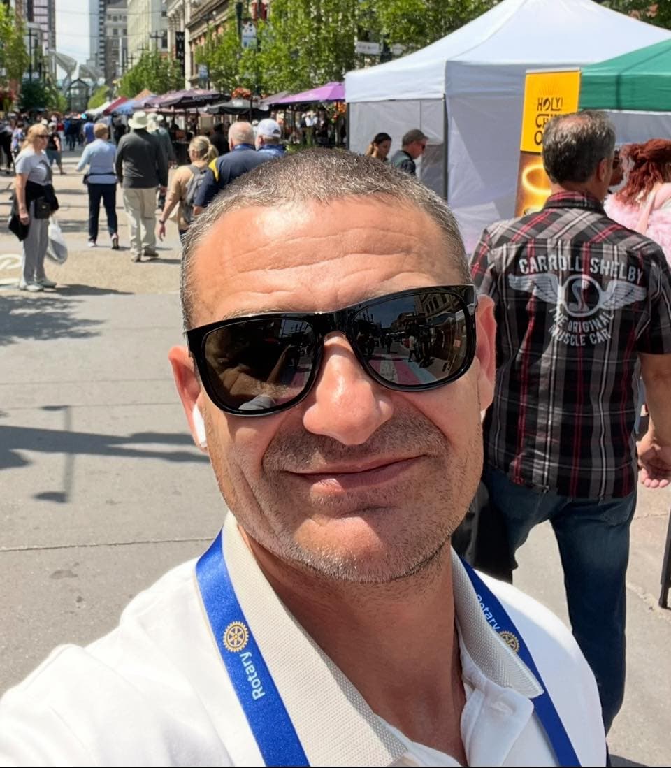 A man wearing sunglasses standing in front of a crowd of people