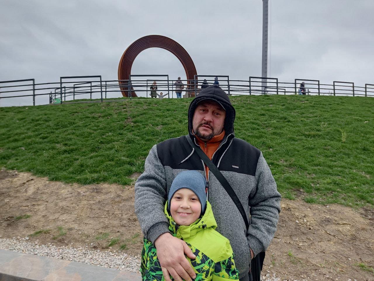 A man and a child standing in front of a sculpture