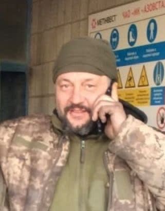 A man in camouflage talking on a cell phone