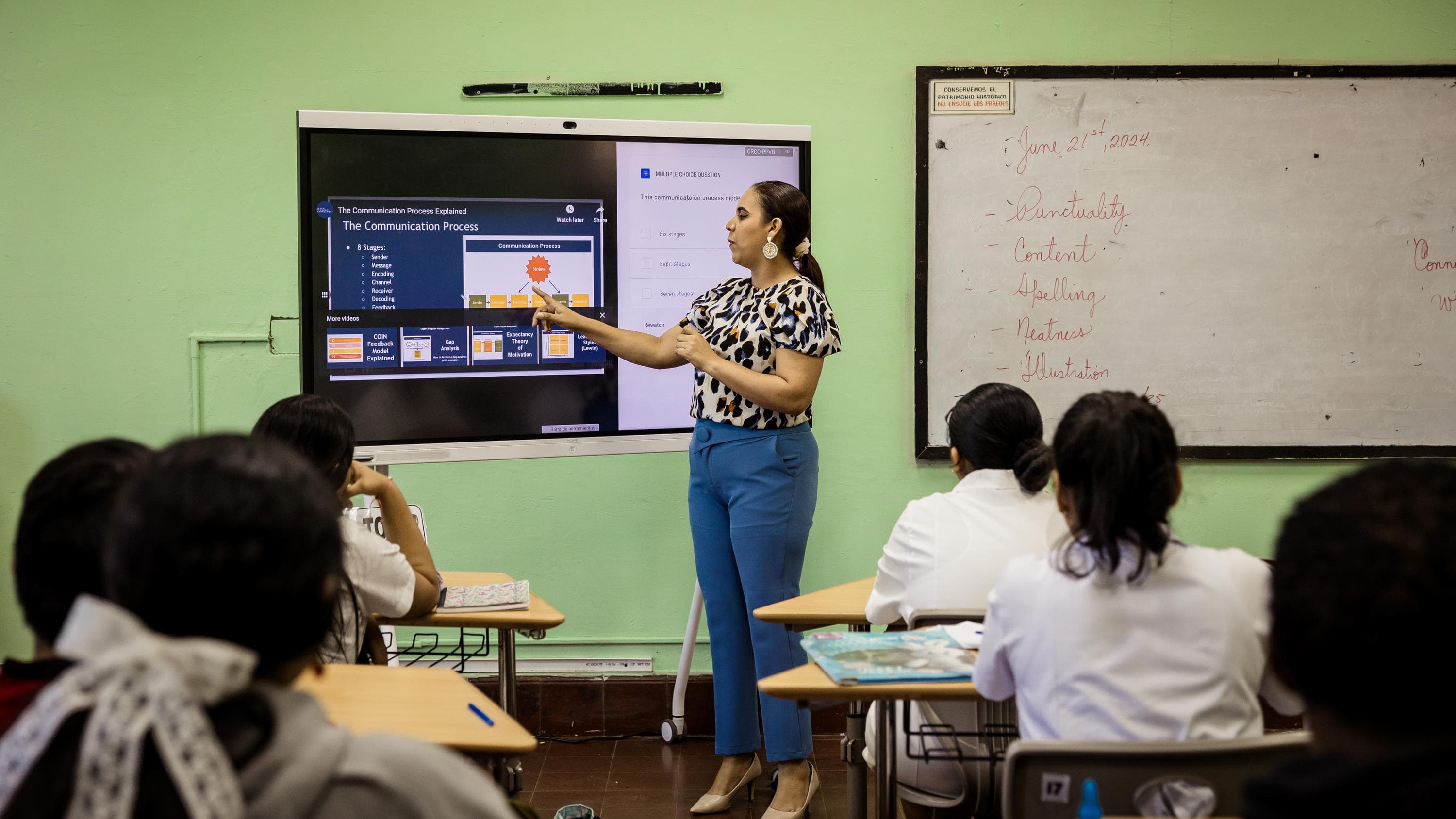 A woman standing in front of a whiteboard in a classroom