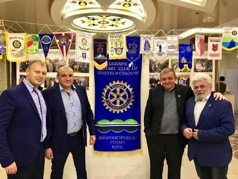 A group of men standing next to each other in front of a banner