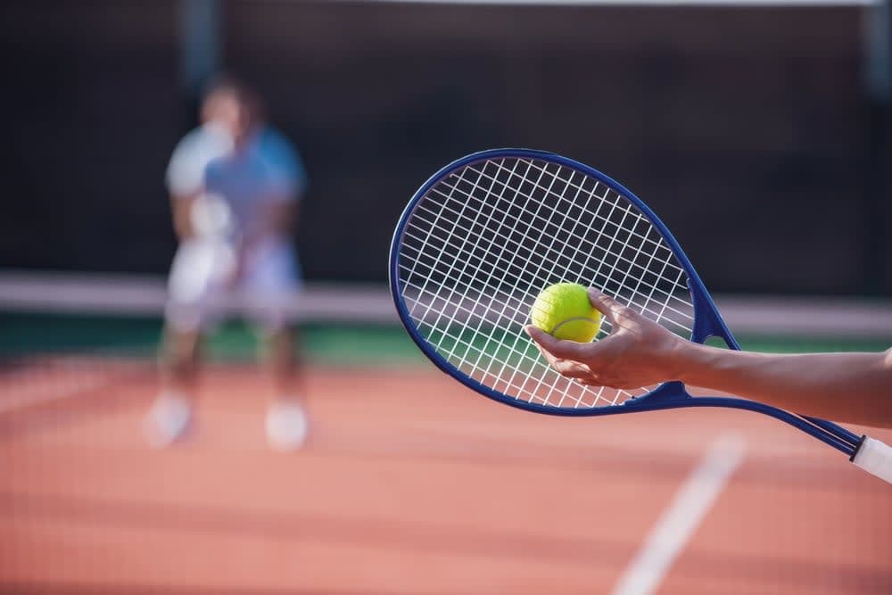 A person holding a tennis racket and a tennis ball