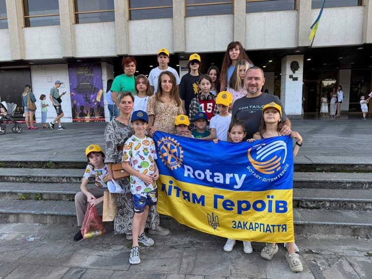 A group of people standing next to each other holding a banner