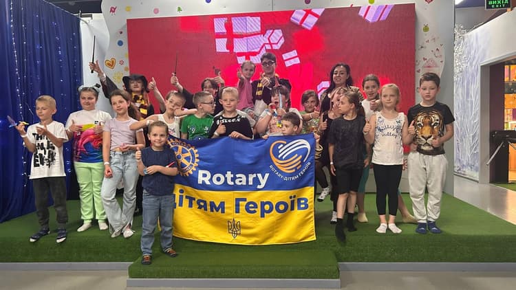 A group of children posing for a picture with a rotary banner