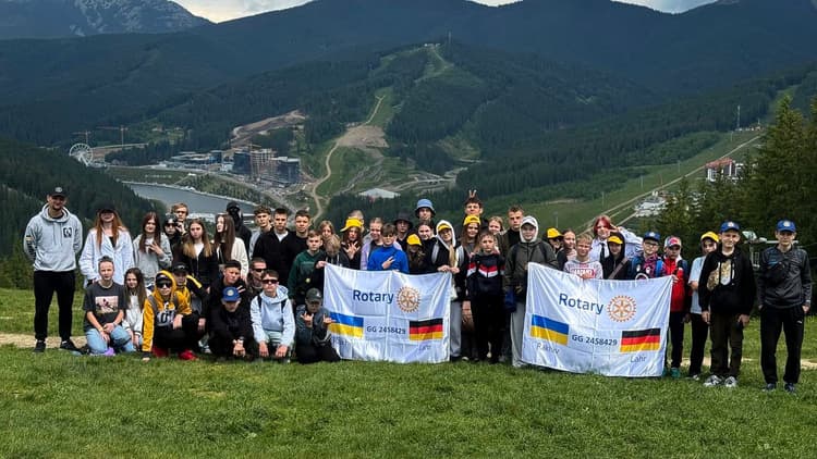 A group of people standing on top of a lush green hillside