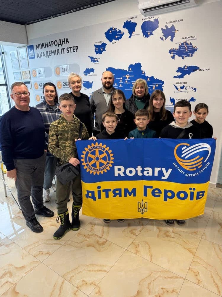 A group of people standing in front of a rotary sign