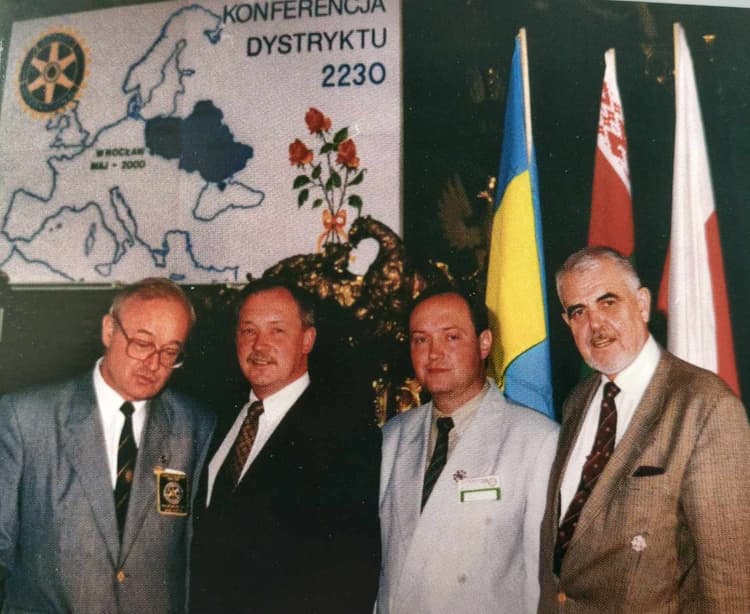 A group of men standing next to each other in front of flags