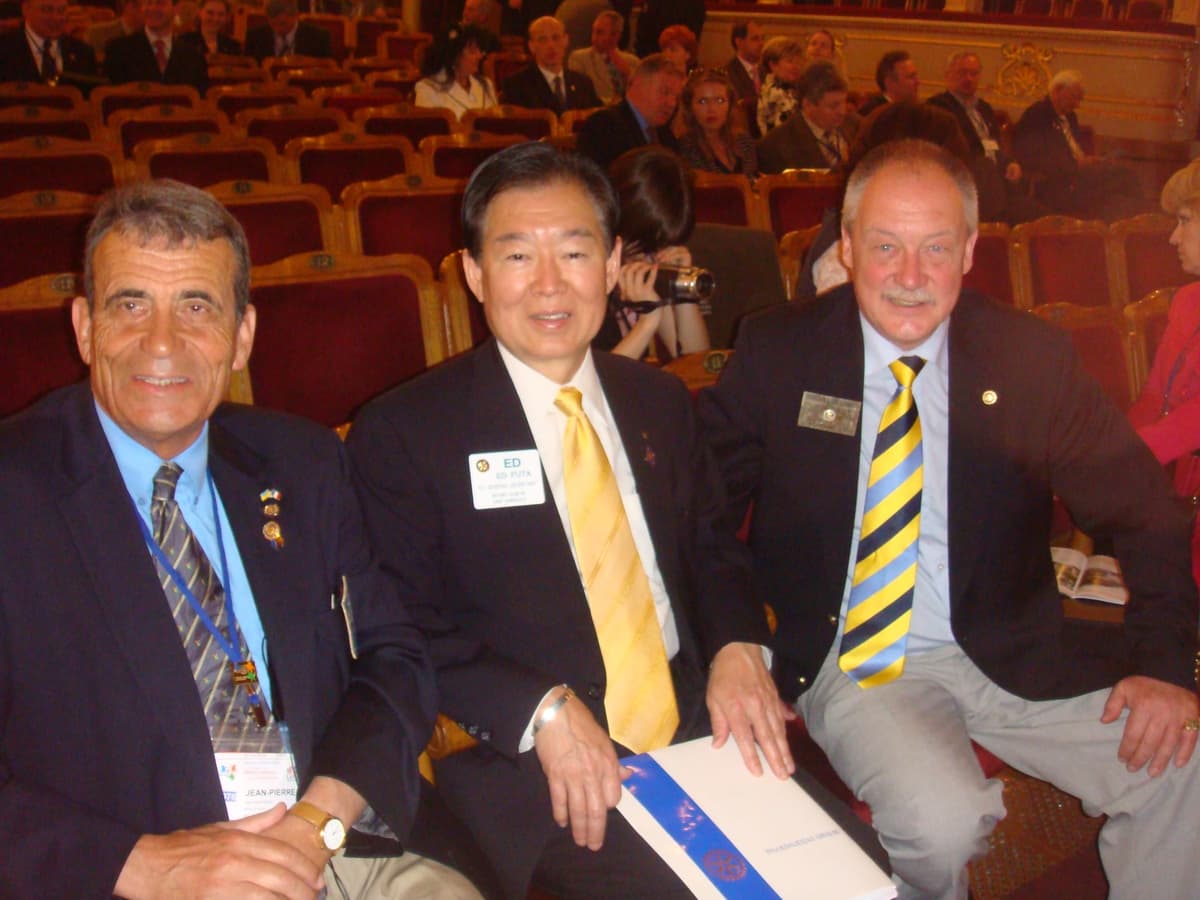 A group of men sitting next to each other in front of a crowd