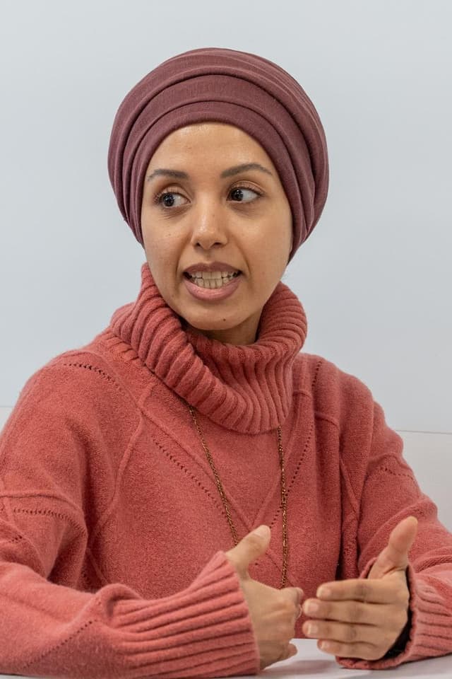 A woman wearing a pink sweater and a turban