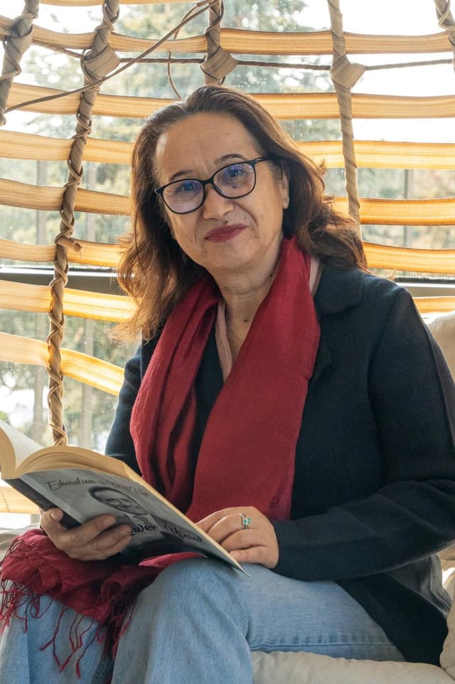 A woman sitting on a swing reading a book