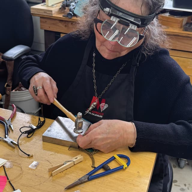 A woman working on a piece of wood with a pair of pliers