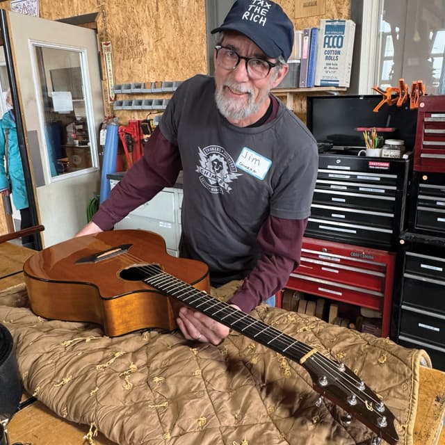 A man sitting on a bed with a guitar