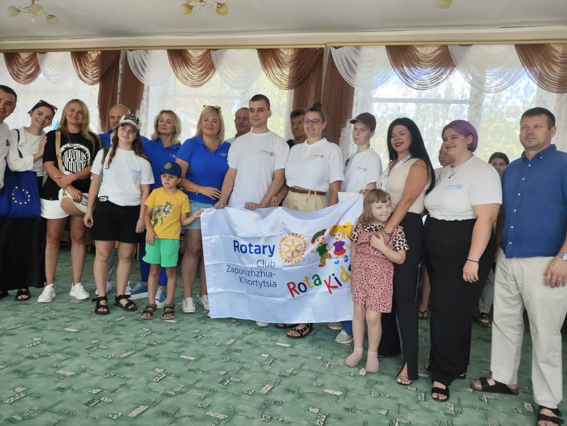 A group of people posing for a picture with a banner