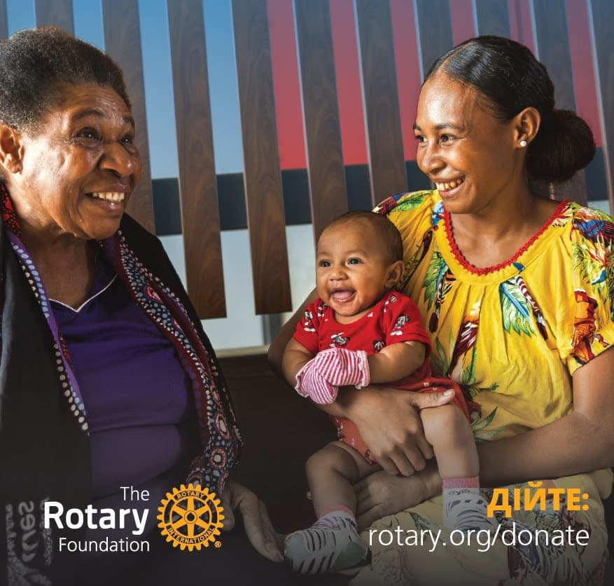 A woman holding a baby next to another woman