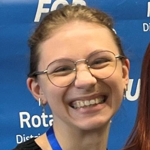 A woman with glasses and a medal around her neck